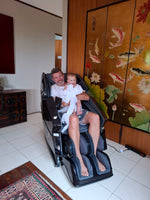 Man and child in a massage chair with a decorative screen in the background